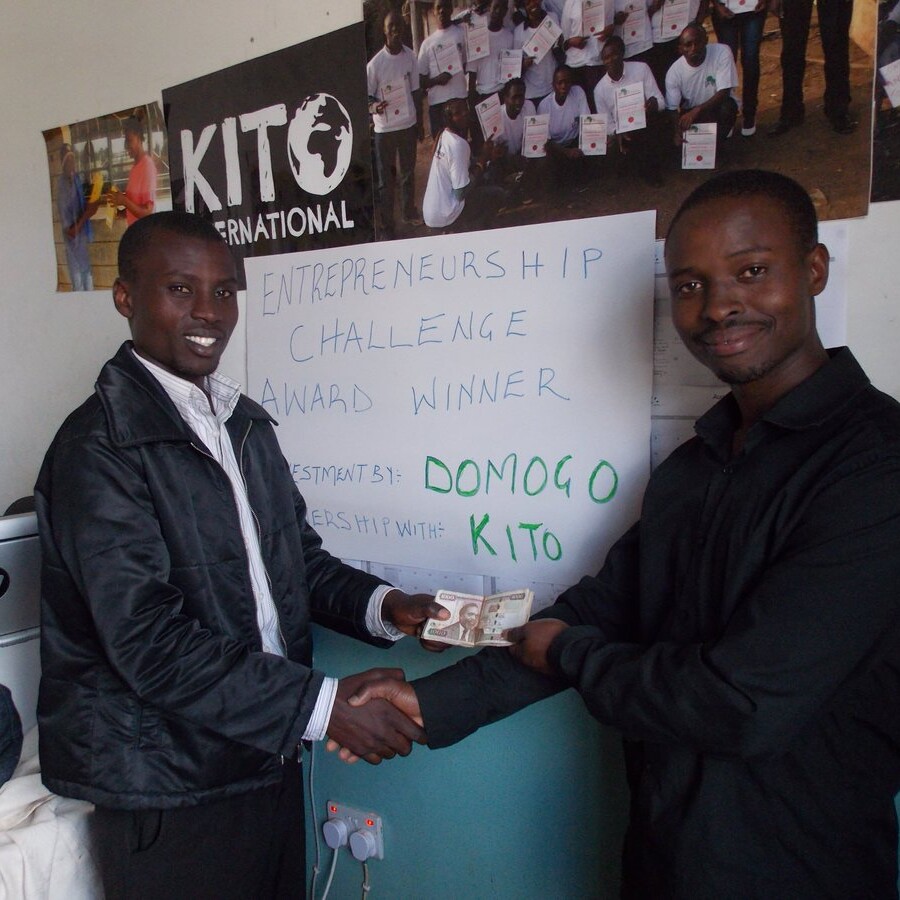 Martin (left), a beneficiary of DOMOGO social entrepreneurship funding through Kito International, receives his cash prize from Wiclif Otieno.