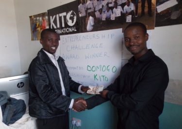 Martin (left), a beneficiary of DOMOGO social entrepreneurship funding through Kito International, receives his cash prize from Wiclif Otieno.
