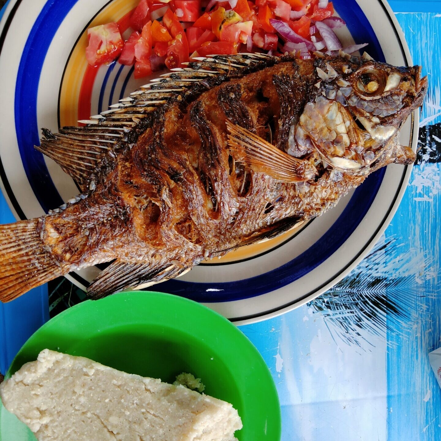 Deep fried fish on a plate with ugali on the side